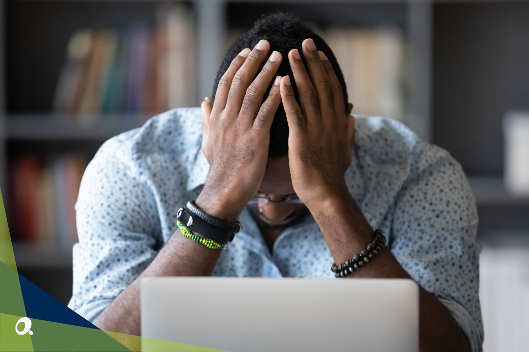 A finance manager surrounded by stacks of paperwork, holding their head in their hands.