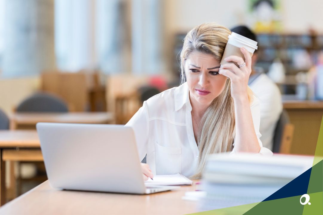 A finance professional holding a cup of coffee, frustrated at using her outdated finance system