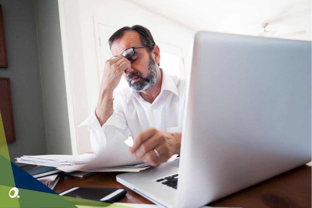 A business owner groaning in frustration, holding a tablet with a financial dashboard displayed.