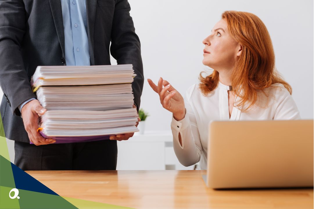 A finance manager being given a fresh stack of paperwork