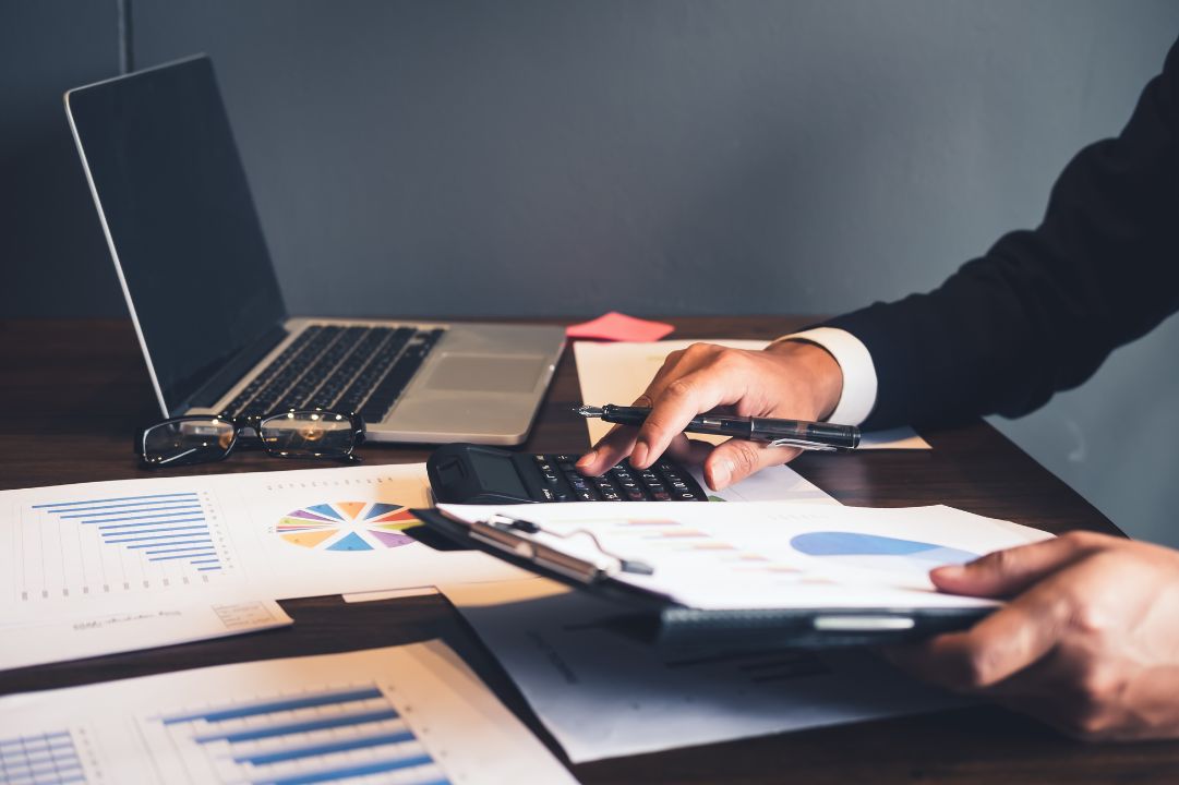 A person holding a clipboard, auditing financials using a calculator