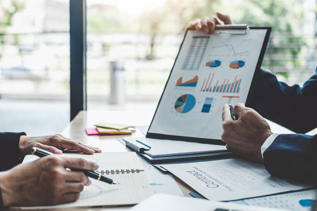 Image of two hands, one holding a clipboard relating to financial risk management and the other taking notes