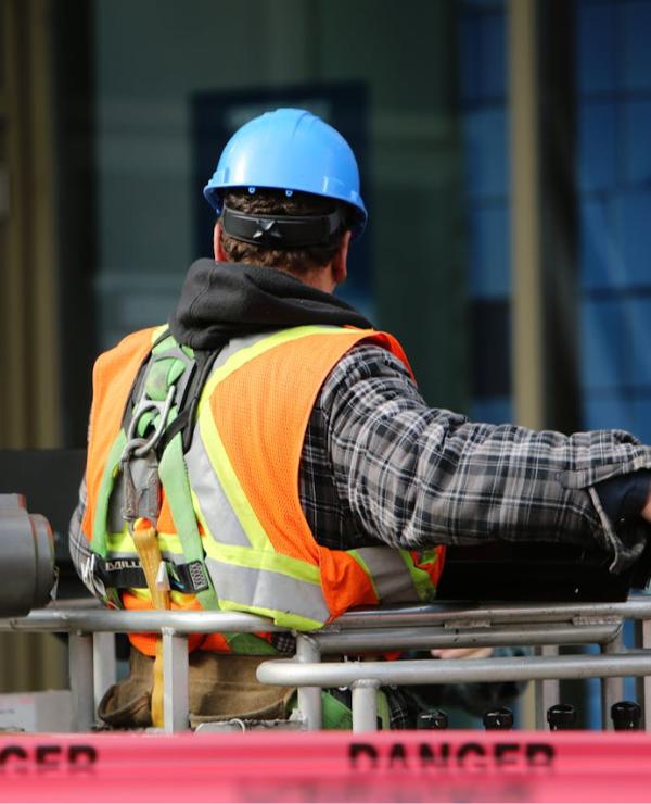 Construction worker reviewing project plans on-site, using a tablet to track costs and budgets with cloud accounting software