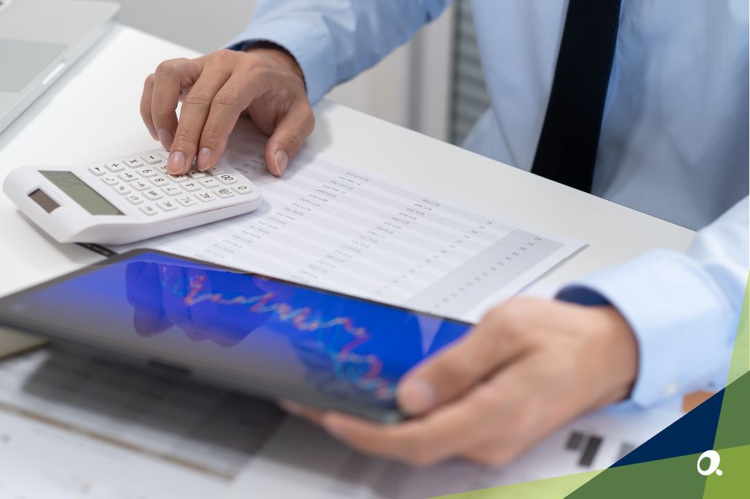 Finance professional using a calculator and tablet to review financial reports, representing the risks of staying on Sage 1000.